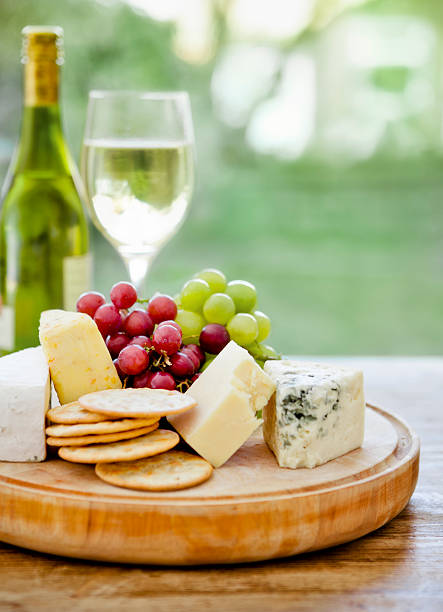 Wooden board with cheese, grapes and wine in the background stock photo