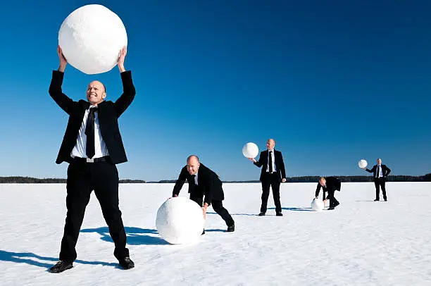 Businessman rolling a snow ball. Business concept to illustrate growth and prosperity.