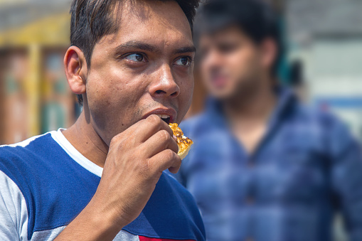 Young Indian Male eating street food, India