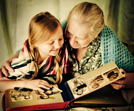 Great-grandmother shows old photos (these are pictures of her and her grandmather) to her great-granddaughter. 