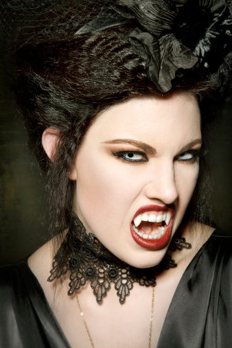 Dramatic portrait of young female with horror black stage makeup painted on face and orange color dreadlocks hairstyle. Studio shot on blue background. Part of photo series