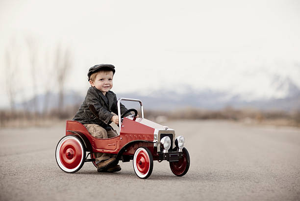 Portrait of an Auto Enthusiast A young boy driver is out for a drive in his pedal car. Vintage black and white. kid toy car stock pictures, royalty-free photos & images