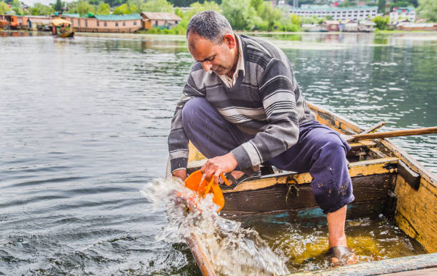 istock An old man removing water which has entered the broken boat. 1171501701