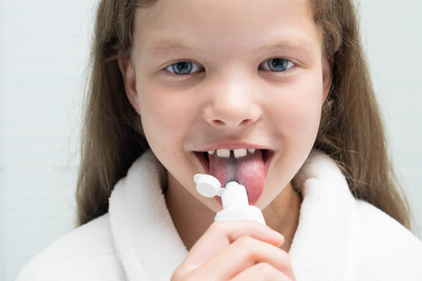 istock girl in a white coat eats toothpaste from a white tube, front view 1171506161