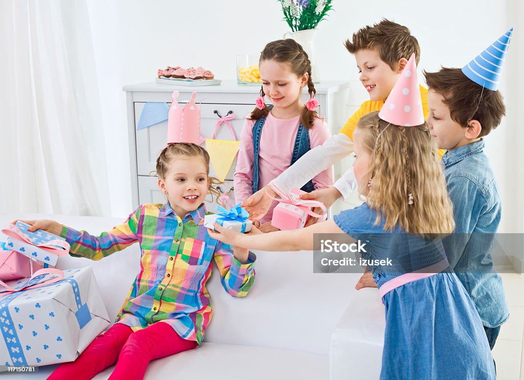 Receiving birthday presents Happy children at Birthday Party. Four cute kids coming to their girlfriend at birthday party and giving to her many presents. Child Stock Photo