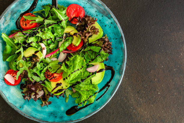 istock salad healthy, vegetables (avocado, tomato, mix leaves, arugula, lettuce, onions and more) top menu concept. food background. copy space 1171508776