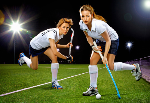 two women playing field hockey