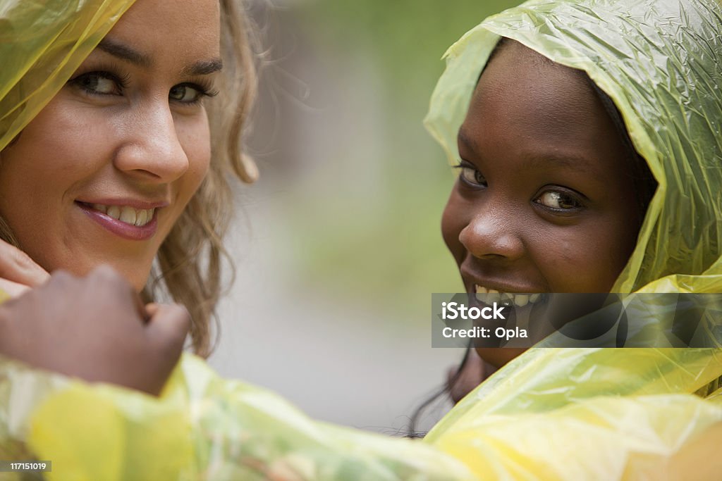 Two friends in raincoats smiling 20-24 Years Stock Photo