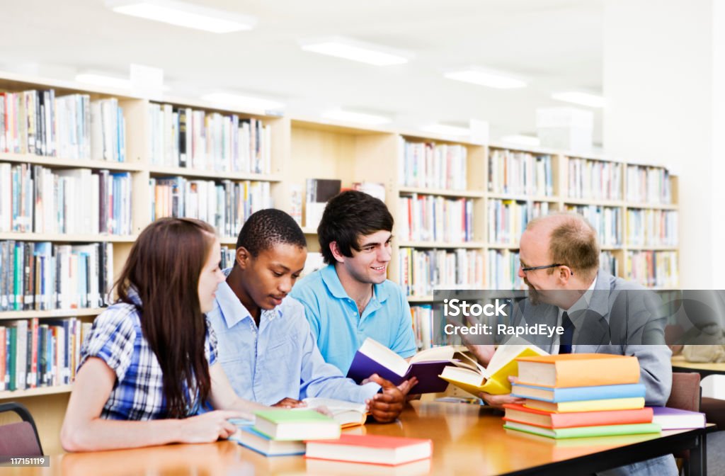 Gruppo di studenti interagiscono con docente in libreria - Foto stock royalty-free di Insegnante