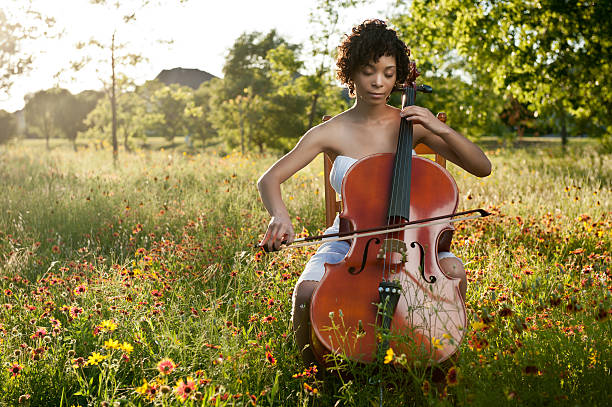 belle jeune femme en train de jouer dans un champ de fleurs sauvages violoncelle - us supreme court photos photos et images de collection