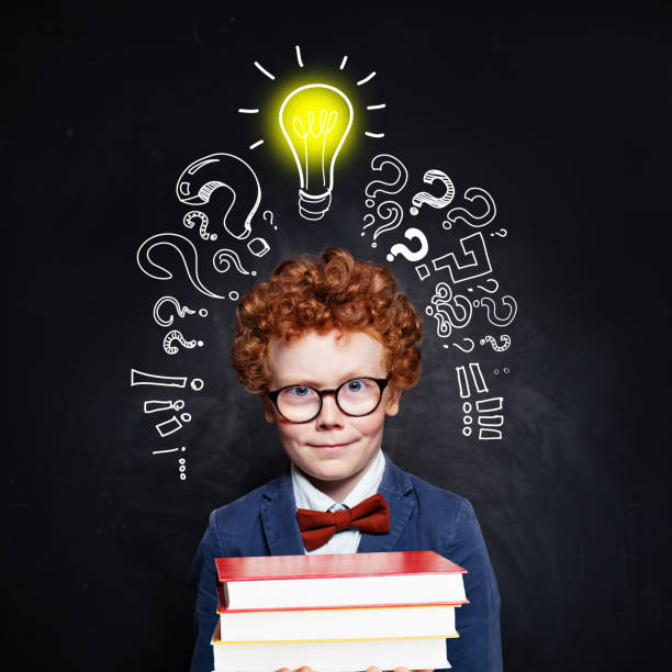 istock Smiling child with lightbulb and books on blackboard background 1171514900