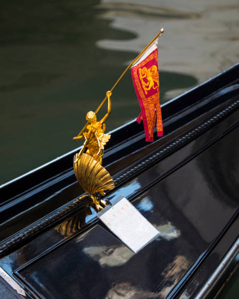 Venice, Italy - July 20th 2019: Close-up detail of a golden sculpture decoration holding the Venetian flag on a Gondola in Venice, Italy.