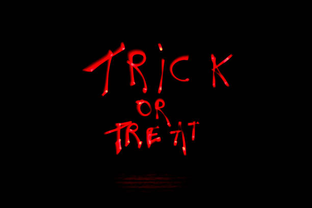 Sentence " trick or treat " written for Halloween with a led lamp during a lightpainting session at night. Abstract curved shape drawn with a light saber. Logo for button web. lightpainting stock pictures, royalty-free photos & images
