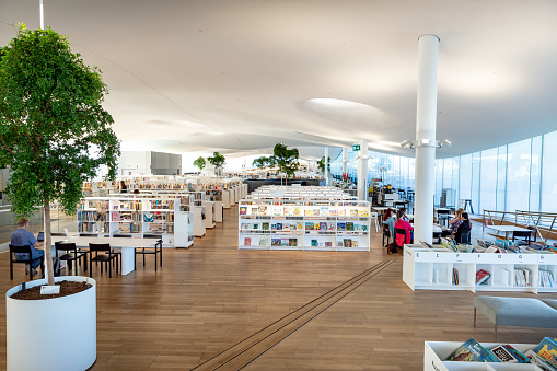 This pic shows New Helsinki central library Oodi interior. Light and spacious modern northern architecture. In the pic Bookshelves, working space. People reading, working, relaxing, studying can be seen. The pic is taken in August 2019.