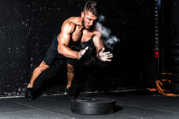 młody muskularny mężczyzna z dużymi spoconymi mięśniami robi trening push ups z klaskaniem ręką nad płytą wagi sztangi na podłodze siłowni z rozmyciem ruchu - shirtless energy action effort zdjęcia i obrazy z banku zdjęć