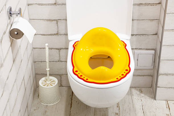 Yellow lid for toilet seat for children. How to accustom a child to the toilet. White bathroom. Yellow lid for toilet seat for children. How to accustom a child to the toilet. White bathroom accustom stock pictures, royalty-free photos & images