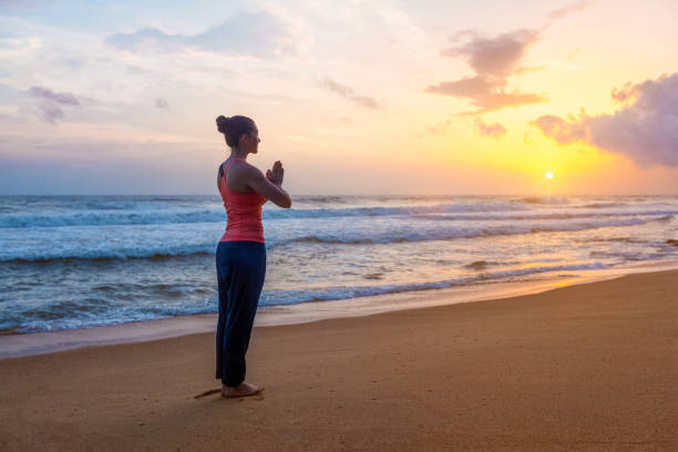 mulher que faz a ioga na praia - saudação ao sol - fotografias e filmes do acervo