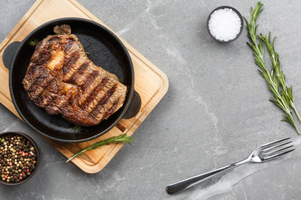 istock fried steak in pan on gray marble table top view 1171552962