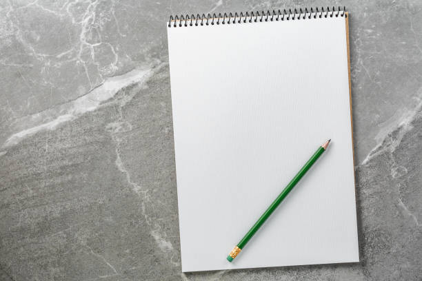 istock notebook with green pencil on marble background, top view 1171553380