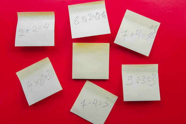 istock Blank yellow sticky notes with mathematical equations and solving them on a red background, concept of business and study work. Yellow commemorative stickers on the red wall. Layout 1171555118