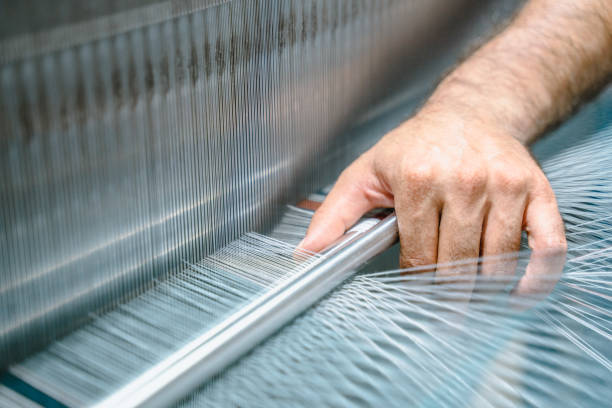 el técnico está comprobando los conos de hilo de bobina en la máquina de haz de deformación industrial en la fábrica textil - weaving machine fotografías e imágenes de stock