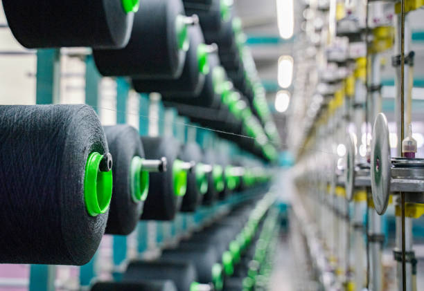 istock Black yarn spools bobbin thread cones on industrial warping beaming machine in textile factory 1171556455