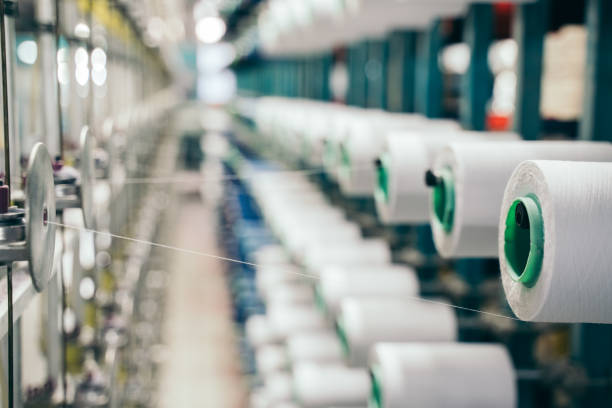 istock White yarn spools bobbin thread cones on industrial warping beaming machine in textile factory 1171556456