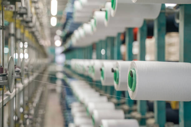 istock White yarn spools bobbin thread cones on industrial warping beaming machine in textile factory 1171556472