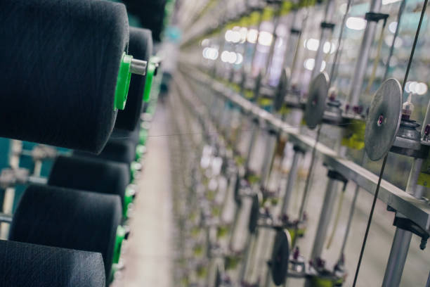 istock Black yarn spools bobbin thread cones on industrial warping beaming machine in textile factory 1171556473