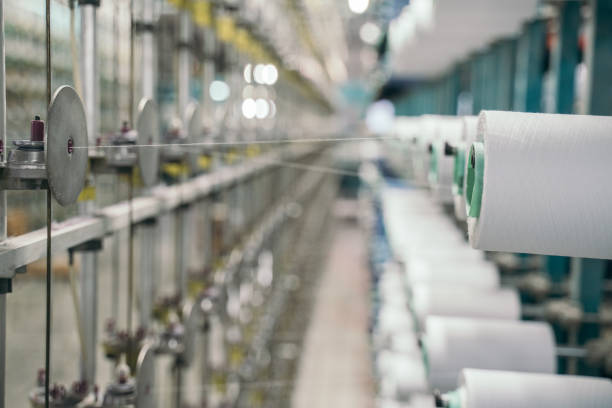 istock White yarn spools bobbin thread cones on industrial warping beaming machine in textile factory 1171556477
