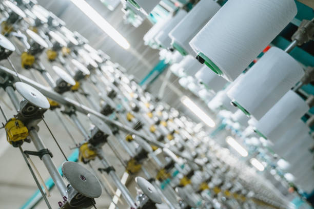 istock White yarn spools bobbin thread cones on industrial warping beaming machine in textile factory 1171556479