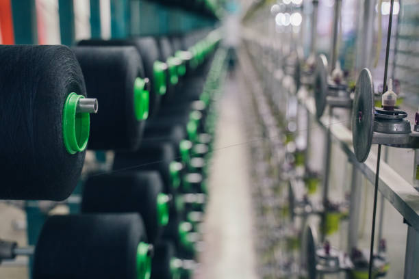istock Black yarn spools bobbin thread cones on industrial warping beaming machine in textile factory 1171556482