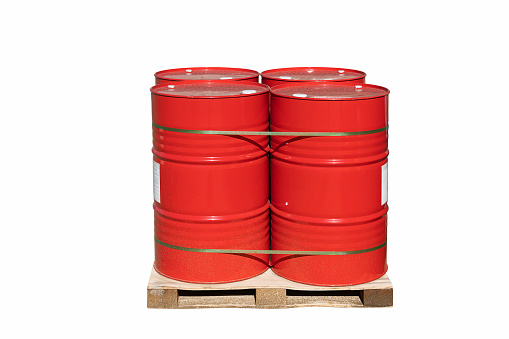 Four red barrels of 200 liters for liquid. Barrels stand on a pallet. Hazardous liquid in steel barrels. Isolated white background.\