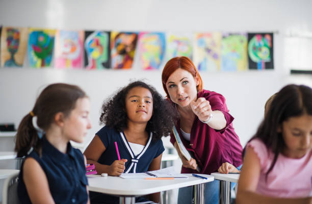 istock A teacher walking among small school children on the lesson, explaining. 1171560855