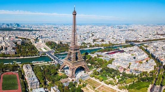 Low angle view of the Eiffel Tower with clear skies and surrounding traffic, capturing the essence of Parisian landmarks.