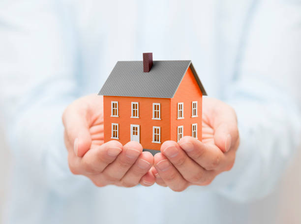 istock Small orange toy house in hands 1171564876