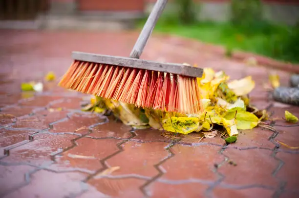 Photo of man cleans with a broom autumn leaves close-up