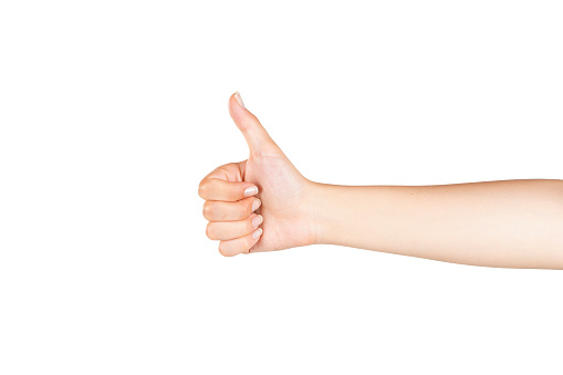 A gentle female hand is making thumbs up OK sign with her right hand on isolated white background.