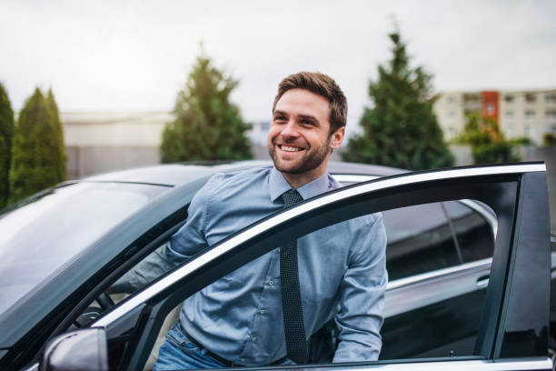 junger mann mit blauem hemd und krawatte, der in der stadt aus dem auto steigt. - shirt necktie men businessman stock-fotos und bilder