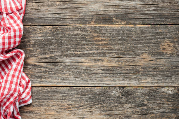 Red checkered picnic textile on rustic wooden planks background. Top view copy space. Cooking, food menu background