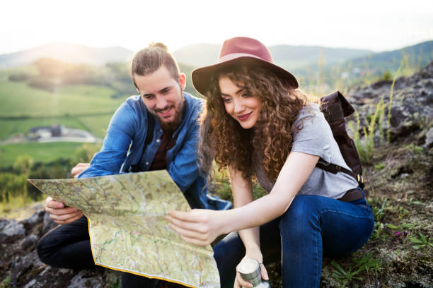 istock Young tourist couple travellers with backpacks hiking in nature, using map. 1171580449