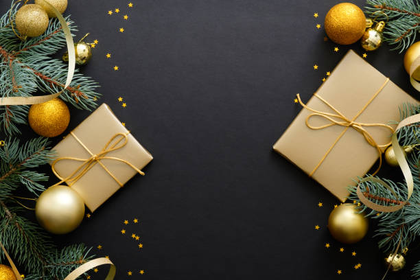 istock Christmas frame. Golden baubles, modern festive decorations, gift boxes, fir tree branches on dark black background. Elegant Christmas greeting card template. Flat lay, top view, copy space. 1171586247