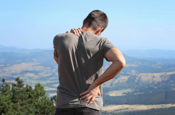 rückenschmerzen linderung. mann wanderer mit rückenschmerzen - pain backache human spine massaging stock-fotos und bilder