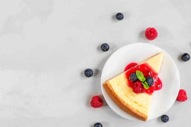 istock slice of classical cheesecake with fresh raspberries, blueberries, jam and mint on marble background. top view 1171594186