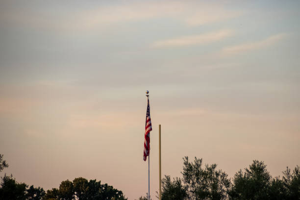 夏の終わりとサッカーシーズンの始まりに日没で見られるサッカーゴールポストの片側の隣にアメリカの旗 - football goal post goal post american football football field ストックフォトと画像