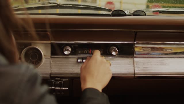 Girl hand tuning radio in a Vintage Classic Car