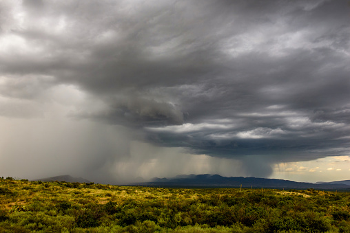 Grand nature scene of mountains and dark storm clouds with an open field. Tetons National Park, Wyoming.