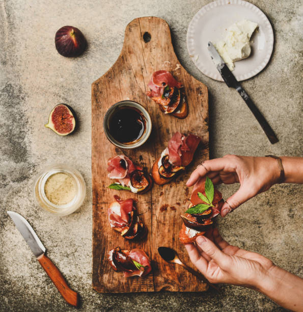istock Crostini with prosciutto, cheese and figs in female hands 1171609810