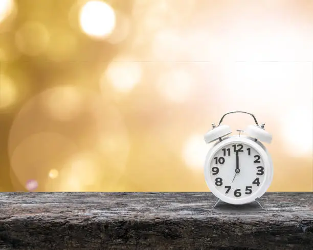 Photo of Daylight saving time end concept with alarm clock on yellow gold autumn blur background