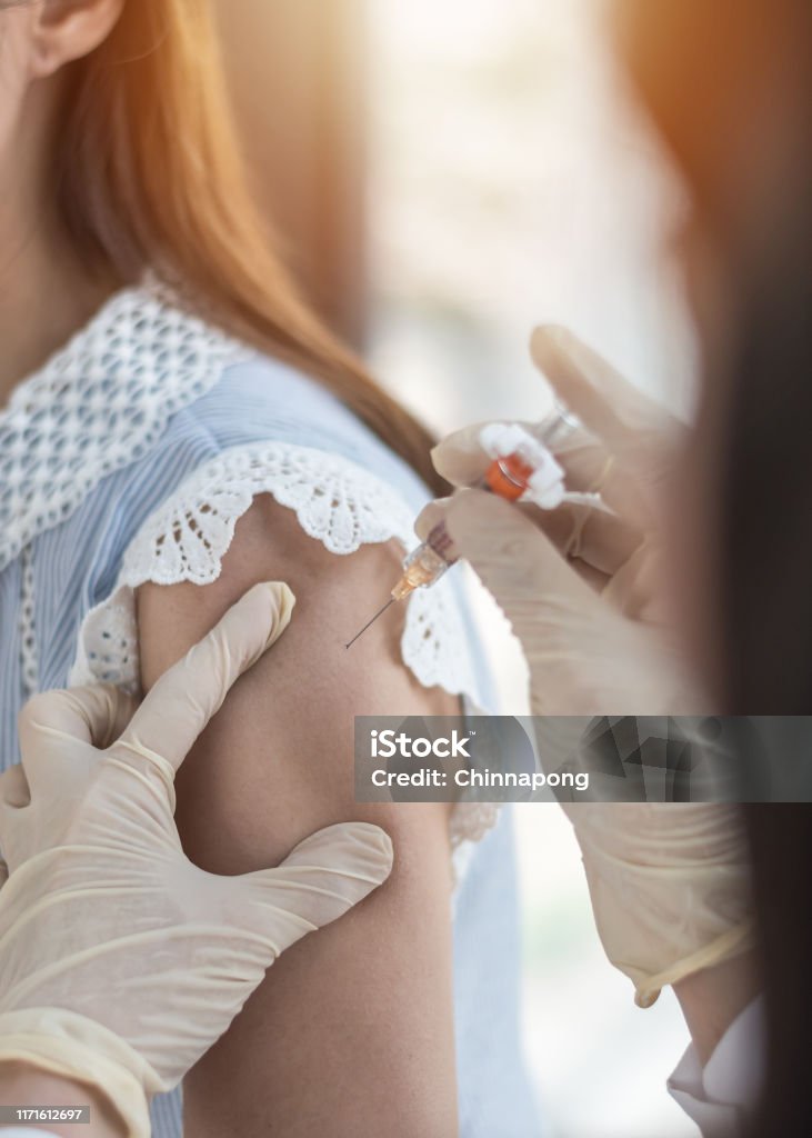 Immunization and vaccination for polio, flu shot, influenza or HPV prevention with woman having vaccine shot with syringe by nurse for World immunization week and International HPV awareness day Polio Vaccine Stock Photo